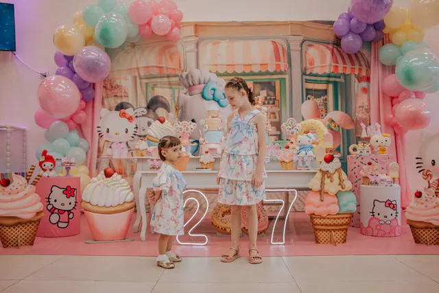Tema doceria da Hello Kitty: duas irmãs em frente à decoração em tons pastel