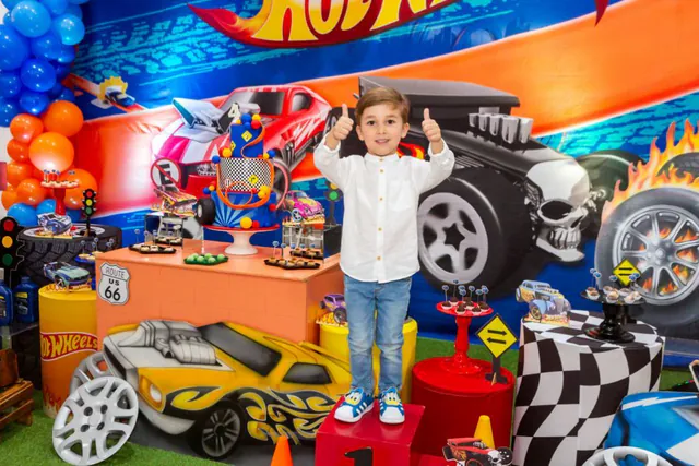 Tema Hot Wheels: menino fazendo joinha em frente à mesa decorada