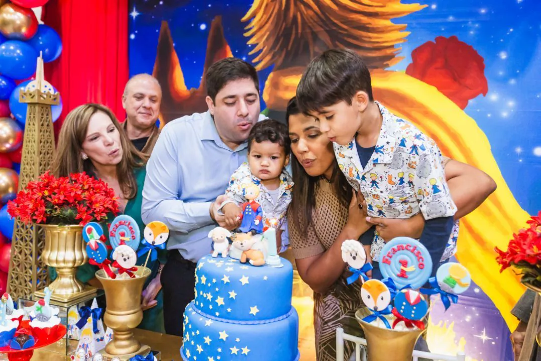 Família soprando as velas do bolo de 1 ano, com tema O Pequeno Príncipe